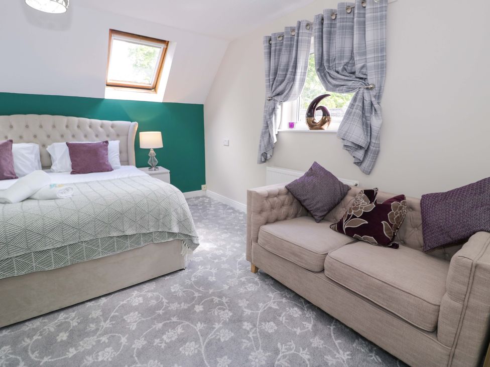 A bedroom with a bed and a sofa at Woodlands Retreat Llanfwrog near Ruthin