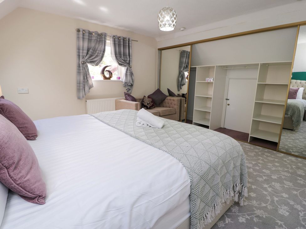 A bedroom with a bed and chair at Woodlands Retreat Llanfwrog near Ruthin