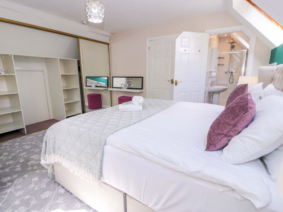 A bedroom with a bed and storage space at Woodlands Retreat in Llanfwrog near Ruthin