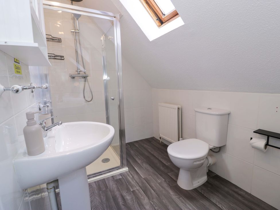 A bathroom with a sink, toilet, and shower at Woodlands Retreat in Llanfwrog near Ruthin