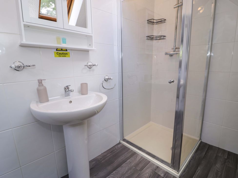 A bathroom with a sink and shower at Woodlands Retreat in Llanfwrog near Ruthin