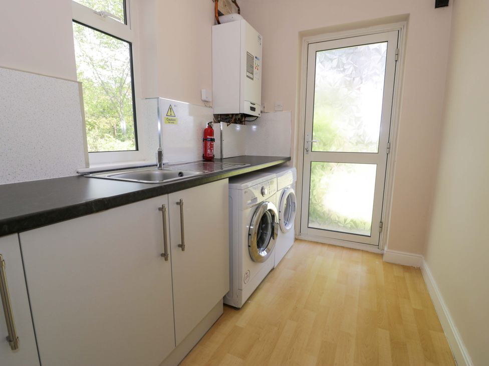 A utility room with a washing machine and sink at Woodlands Retreat Llanfwrog near Ruthin