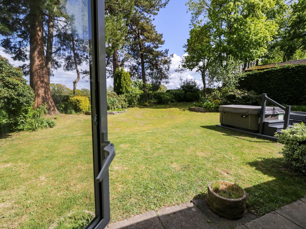 A garden with a hot tub and trees at Woodlands Retreat Llanfwrog near Ruthin