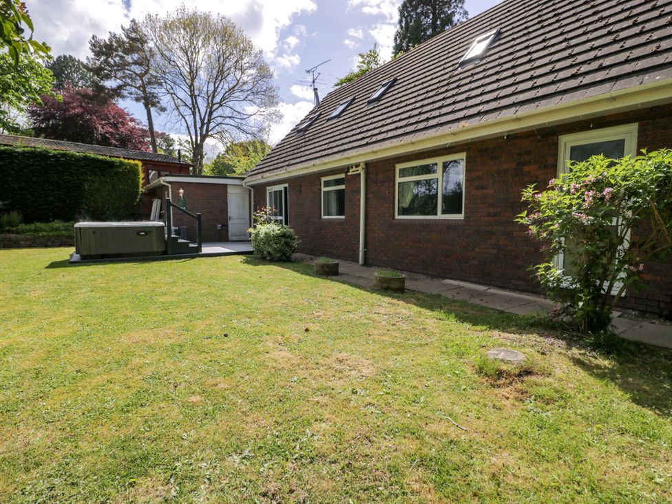 A garden with a house and a spa at Woodlands Retreat in Llanfwrog near Ruthin