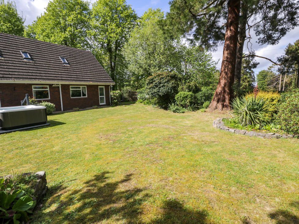 A garden with a house and hot tub at Woodlands Retreat Llanfwrog near Ruthin