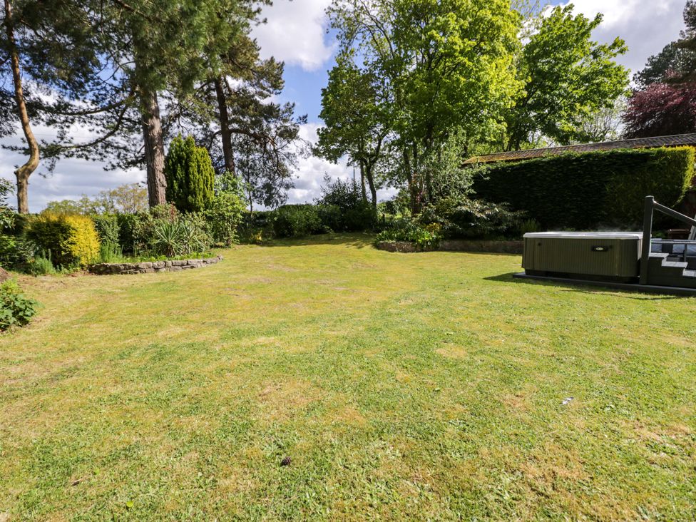 A garden with a hot tub and trees at Woodlands Retreat Llanfwrog near Ruthin