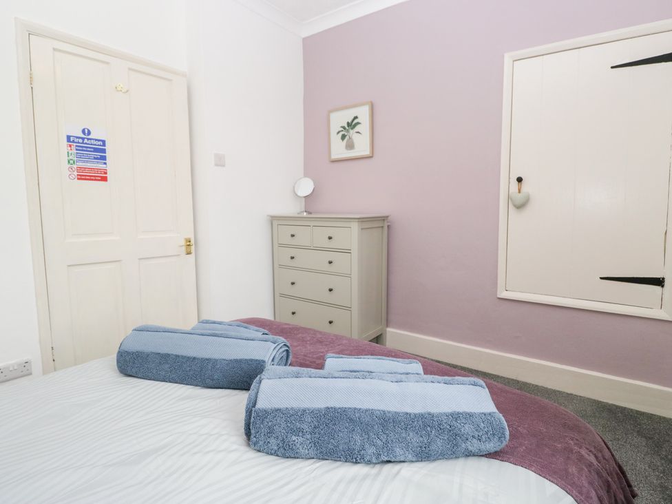 A bedroom with a bed and towels on top at 3 Nixon Terrace Broughton Moor near Maryport