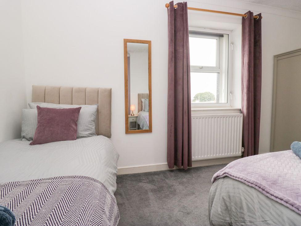 A bedroom with two beds and a mirror at 3 Nixon Terrace near Broughton Moor
