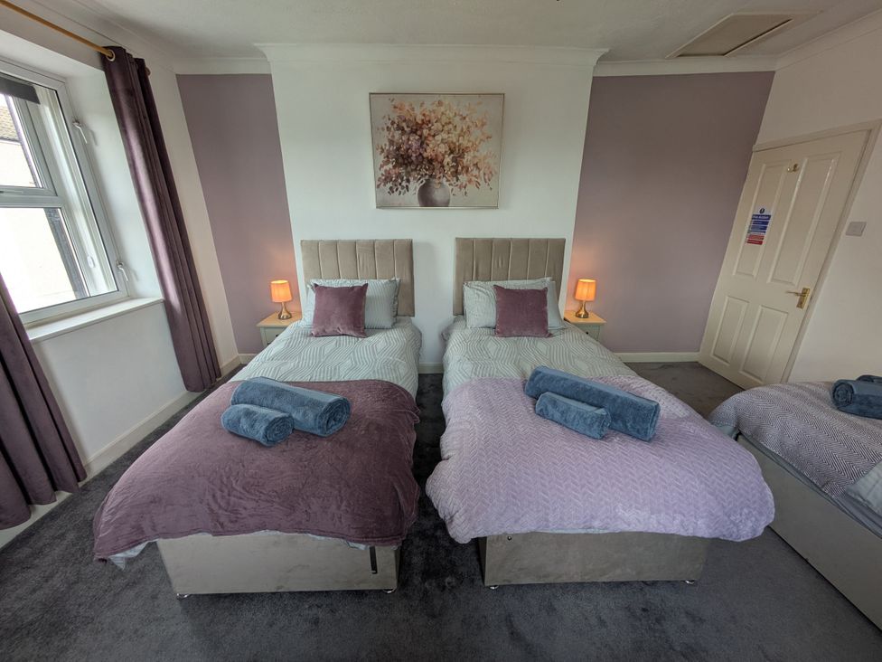 A bedroom with two beds and a lamp at 3 Nixon Terrace Broughton Moor near Maryport