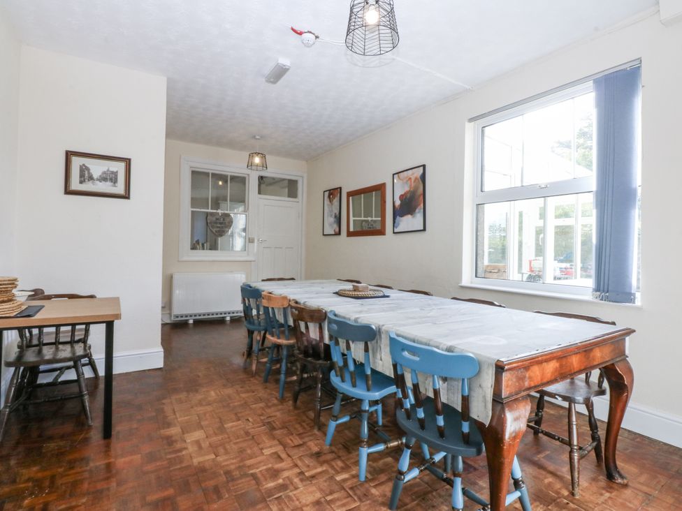 A dining room with a long table and blue chairs at Tawelfan in Llwyngwril