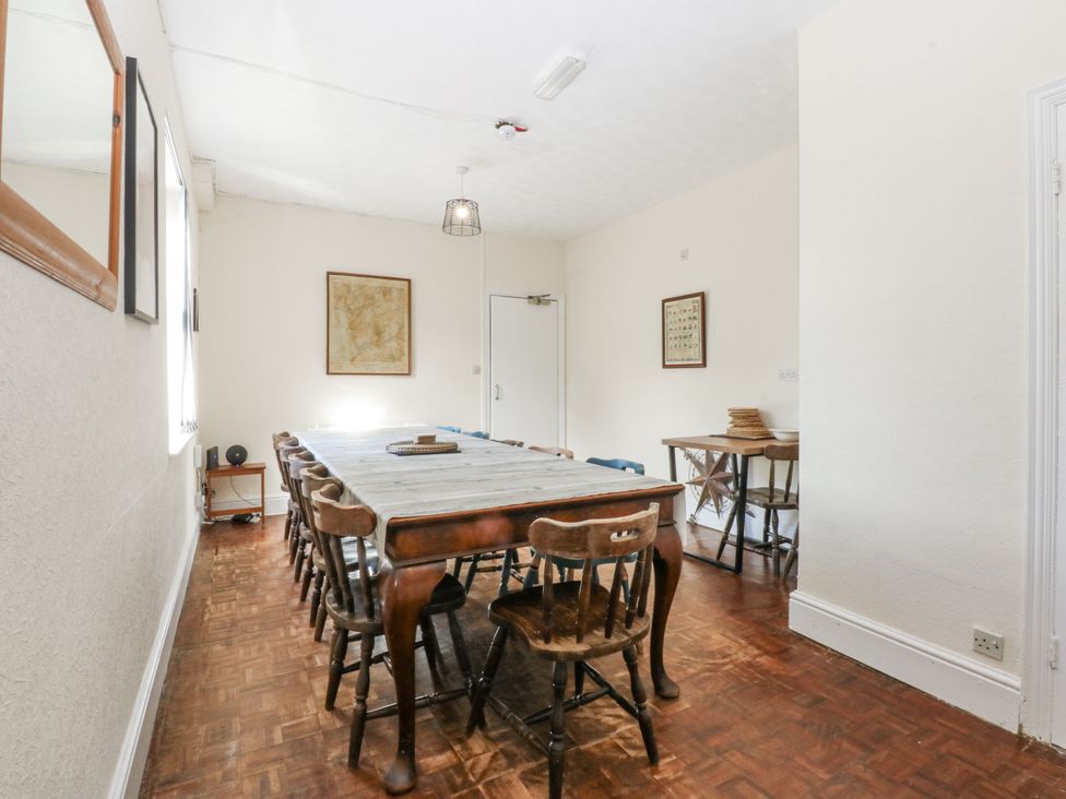 A dining room with a long table and chairs at Tawelfan in Llwyngwril