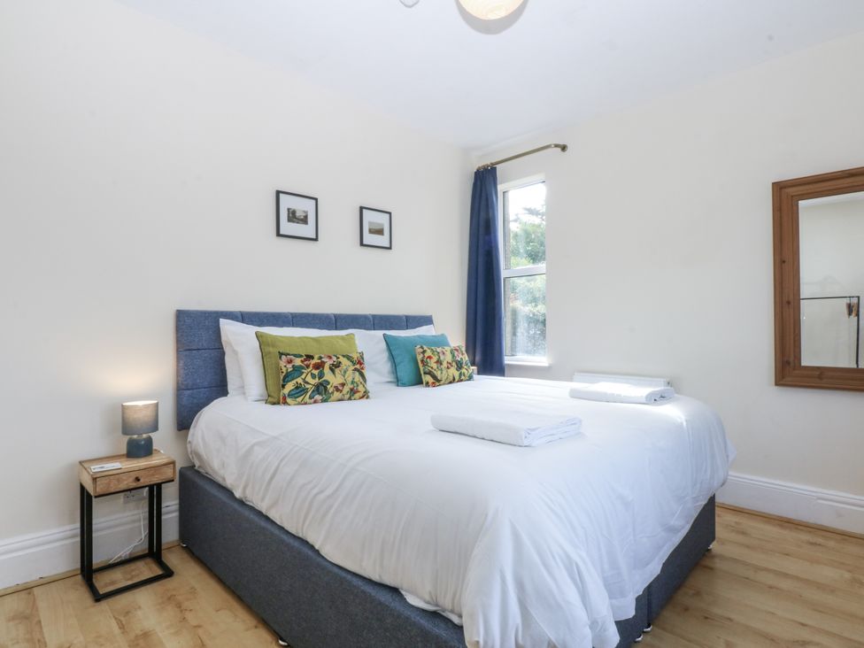 A bedroom with a bed, nightstand, and window at Tawelfan in Llwyngwril