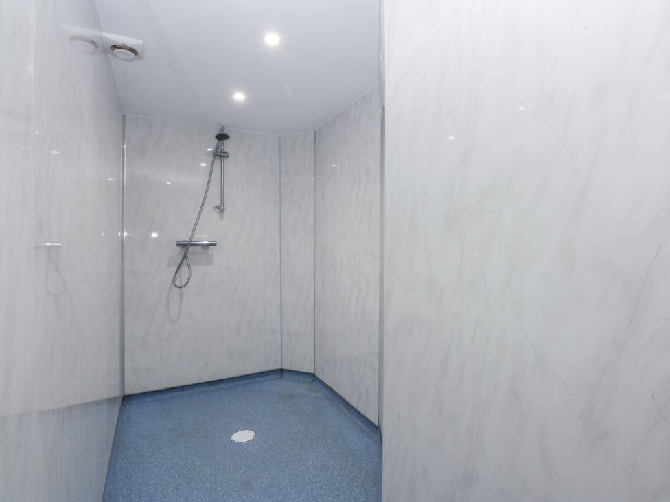 A shower area with a wall and showerhead at Tawelfan in Llwyngwril