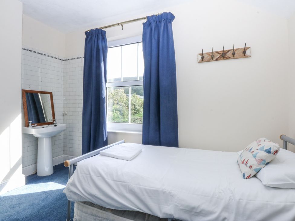 A bedroom with a bed, sink, mirror, and window at Tawelfan in Llwyngwril
