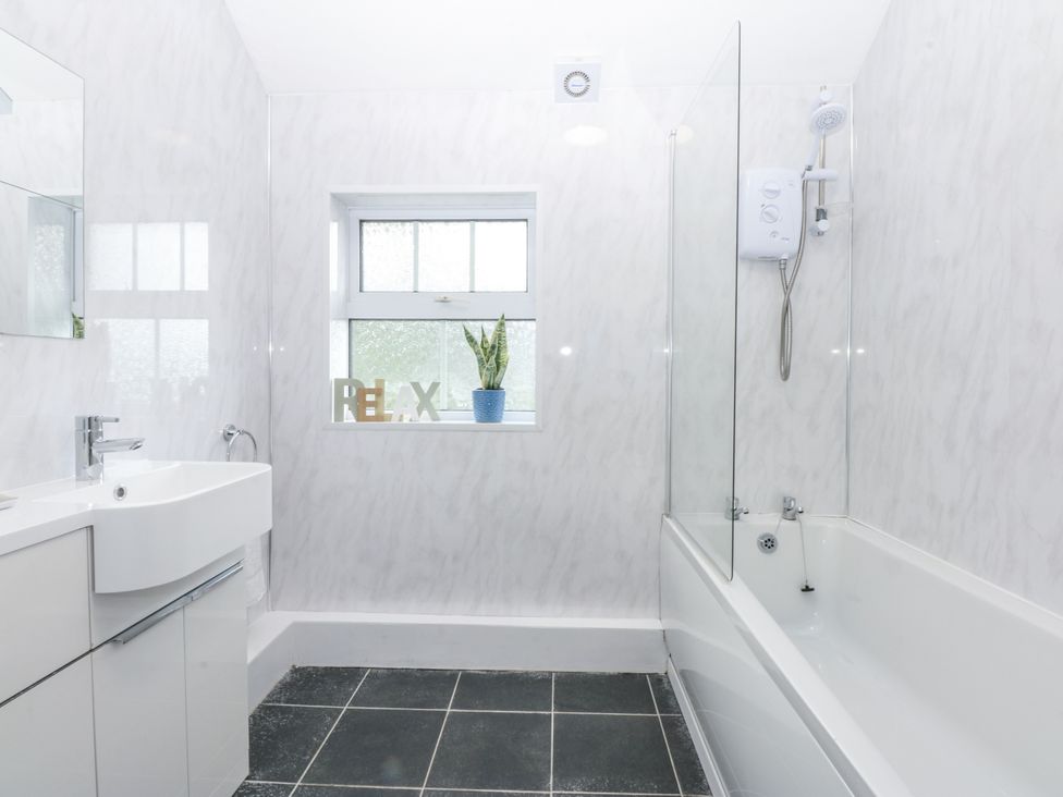 A bathroom with a sink, bathtub, and shower at Tawelfan in Llwyngwril