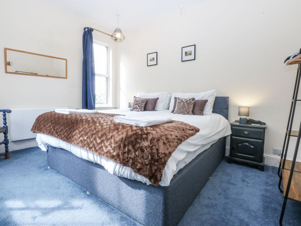 A bedroom with a bed, nightstand, and window at Tawelfan in Llwyngwril