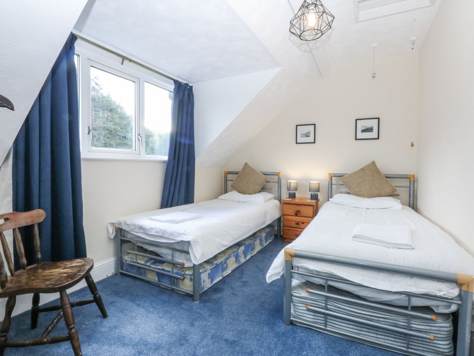 A bedroom with two beds and a chair at Tawelfan in Llwyngwril