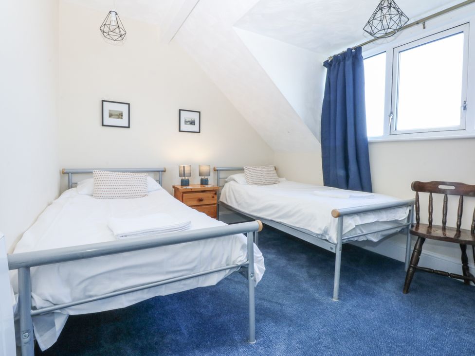 A bedroom with two beds and a chair at Tawelfan in Llwyngwril
