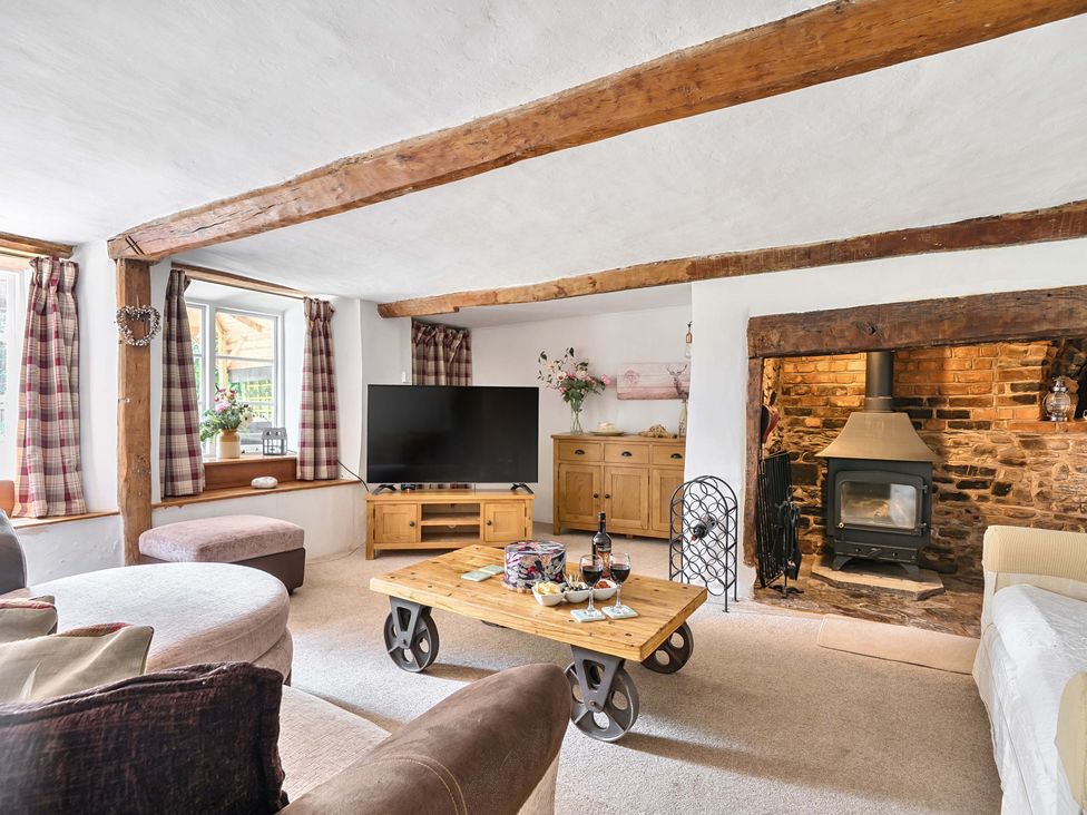 A living room with a sofa, television, and fireplace at 2 Pigsfoot Cottages Ash Thomas near Halberton, Devon