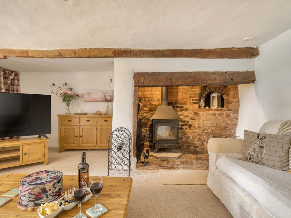 A living room with a wooden cabinet and television at 2 Pigsfoot Cottages Ash Thomas near Halberton, Devon