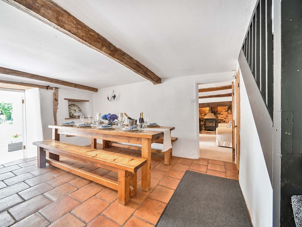 A dining room with a wooden table and benches at 2 Pigsfoot Cottages Ash Thomas near Halberton, Devon