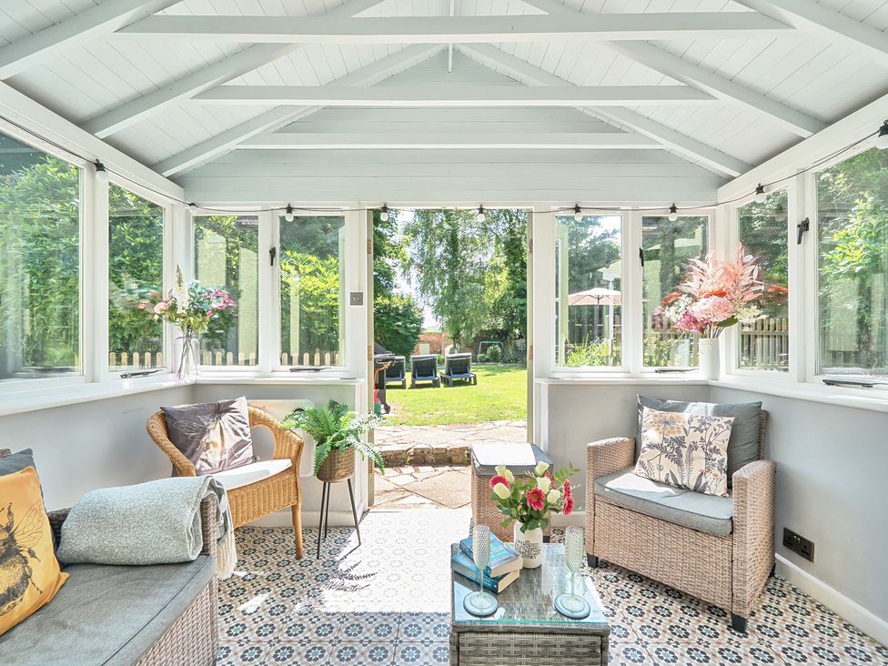 A conservatory with seating and a garden view at 2 Pigsfoot Cottages Ash Thomas near Halberton, Devon
