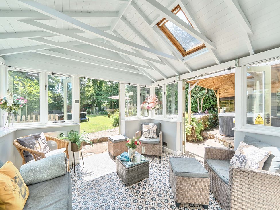 A conservatory with seating and a view of the garden at 2 Pigsfoot Cottages Ash Thomas near Halberton, Devon