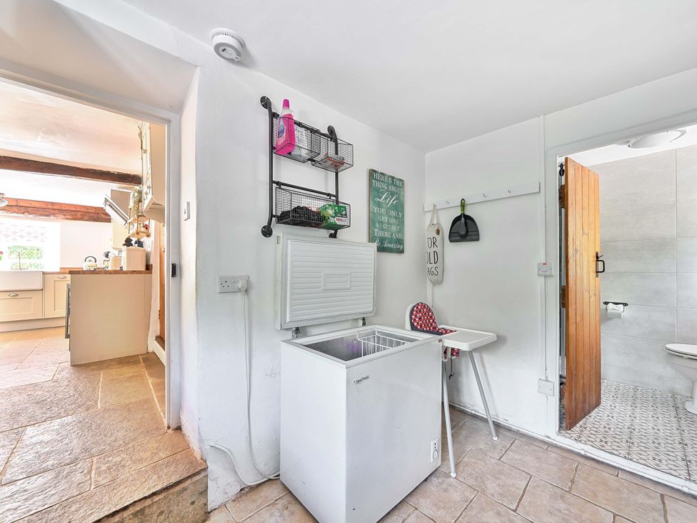 A utility room with a freezer and a door to a bathroom at 2 Pigsfoot Cottages Ash Thomas near Halberton, Devon