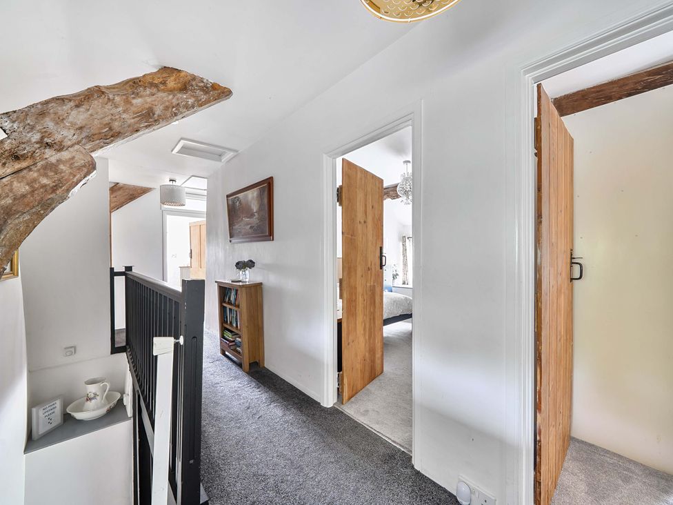 A hallway with wooden doors and a bookshelf at 2 Pigsfoot Cottages, Ash Thomas near Halberton, Devon
