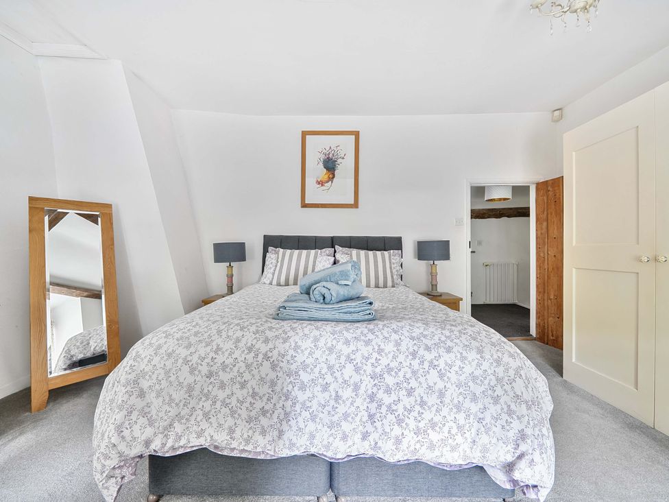 A bedroom with a bed and a mirror at 2 Pigsfoot Cottages Ash Thomas near Halberton, Devon