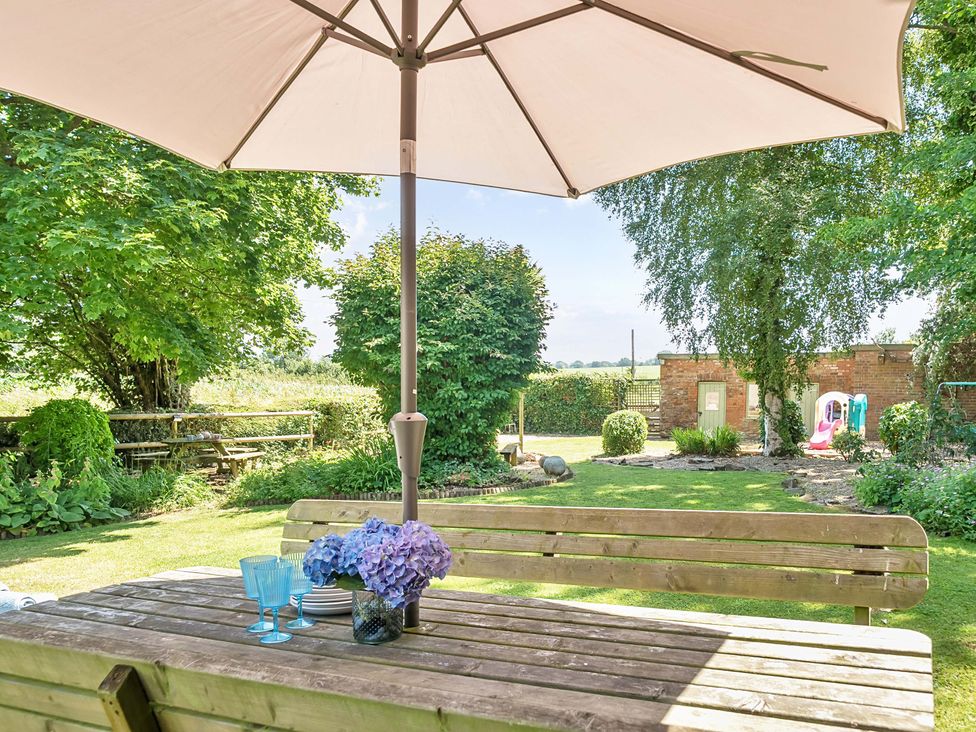 An outdoor dining area with flowers and glasses at 2 Pigsfoot Cottages Ash Thomas near Halberton, Devon