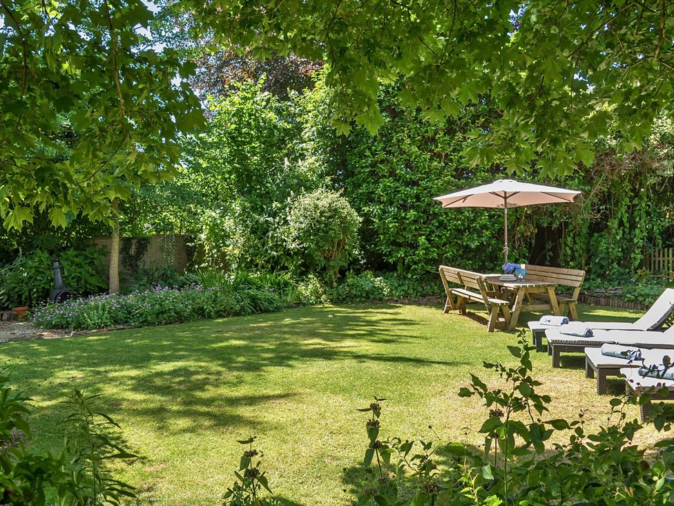A garden with a table and chairs under a parasol at 2 Pigsfoot Cottages Ash Thomas near Halberton, Devon