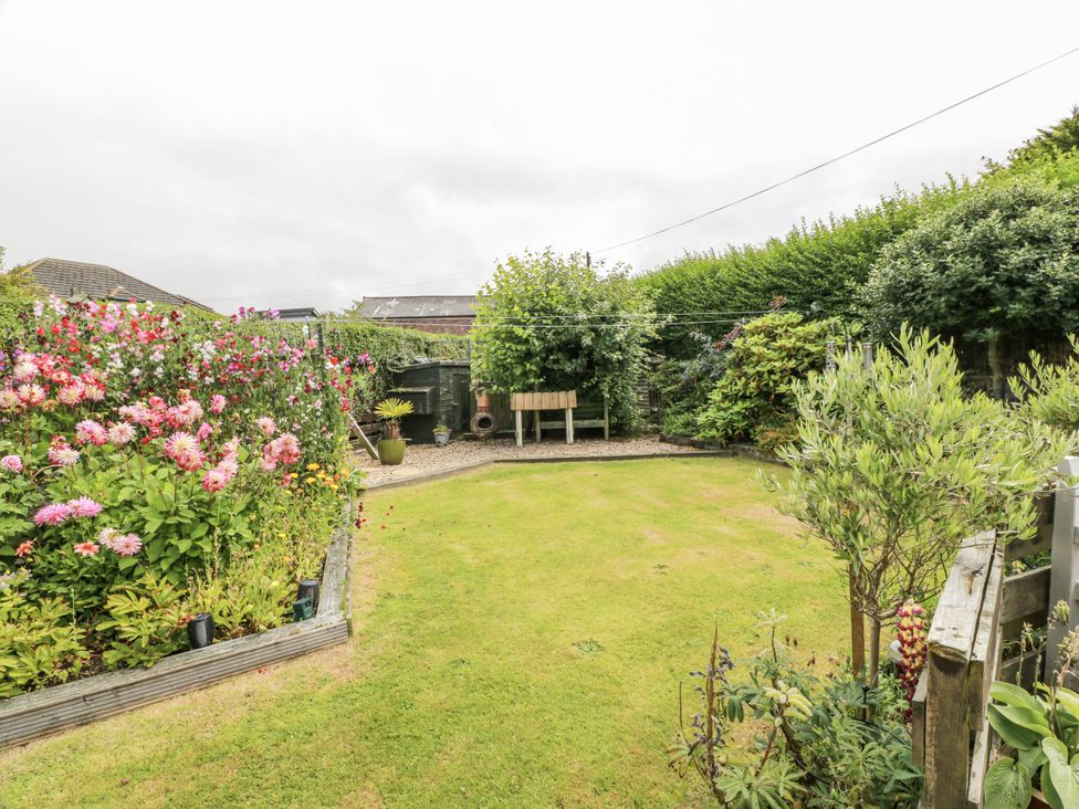 A garden with flowers, a bench, and grass at Learig Cottage in Girvan