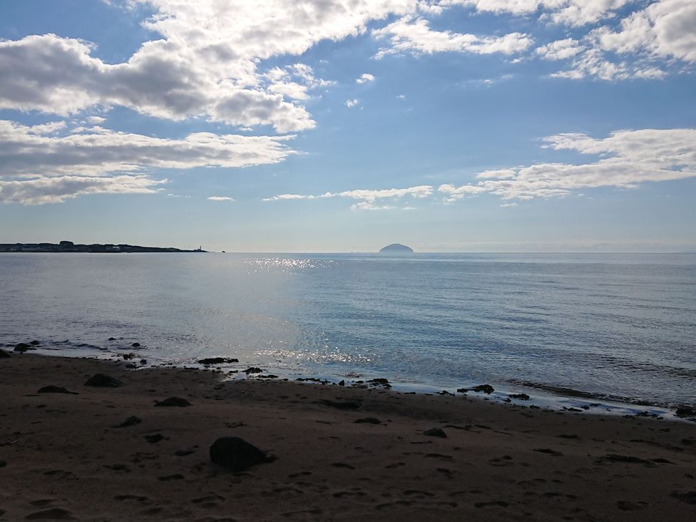 A beach with sand and sea under a cloudy sky at Learig Cottage Girvan