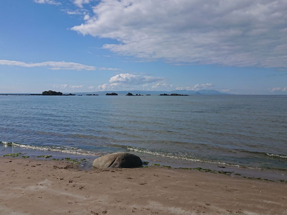 A beach with water and rocks at Learig Cottage in Girvan
