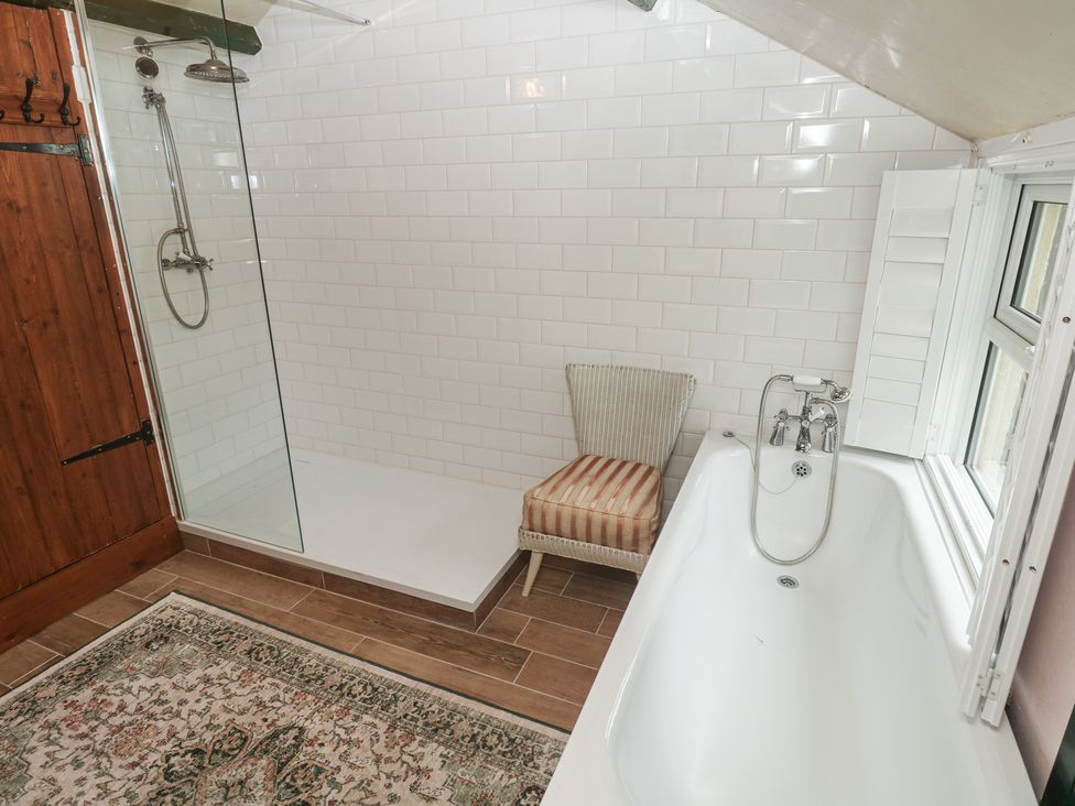 A bathroom with a shower, bathtub, and chair at Pentira in Kuggar