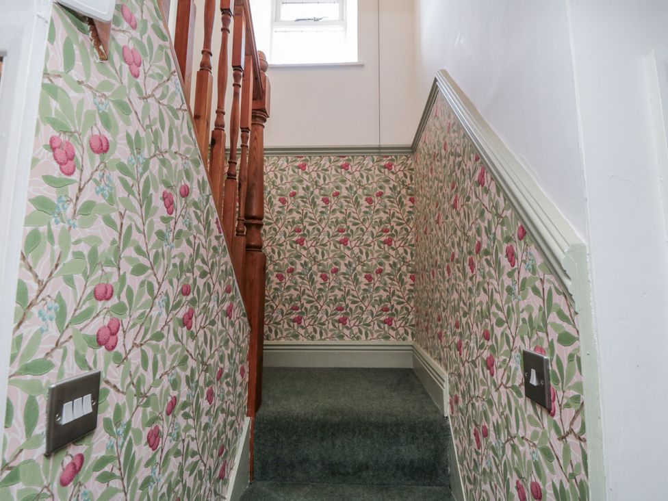 A stairway with patterned wallpaper and a light switch at Inglenook Cottage, Guisborough