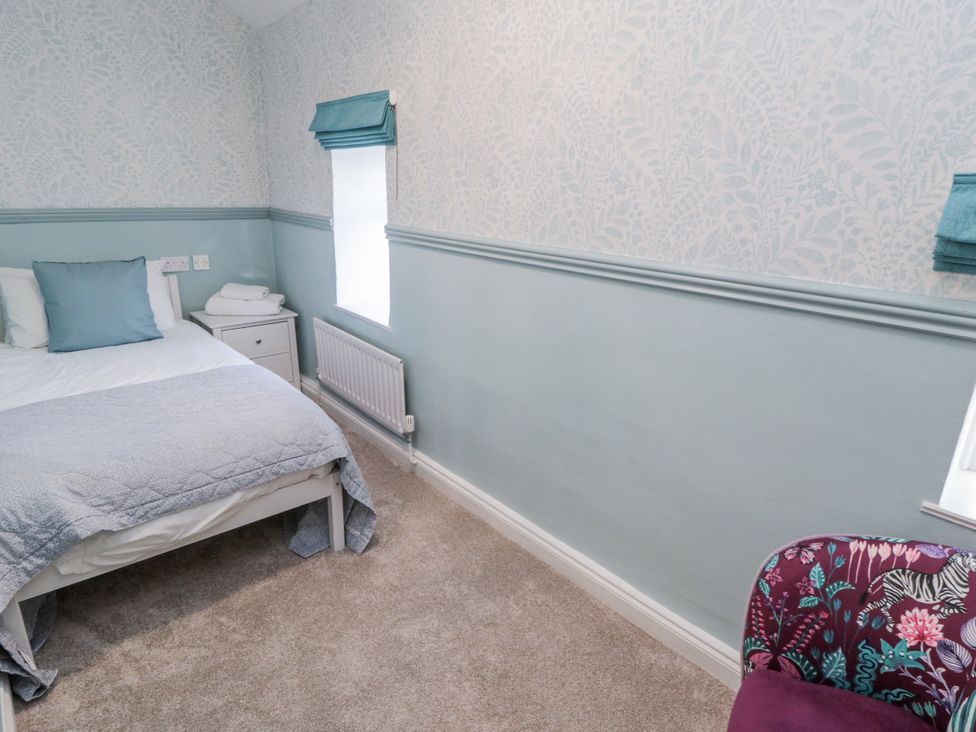 A bedroom with a bed and chair at Inglenook Cottage in Guisborough