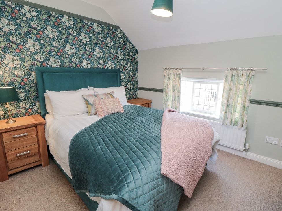 A bedroom with a bed and nightstand at Inglenook Cottage in Guisborough