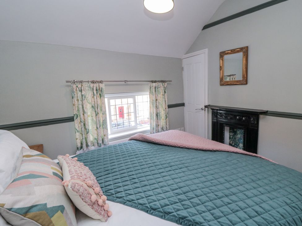 A bedroom with a bed and curtains at Inglenook Cottage in Guisborough