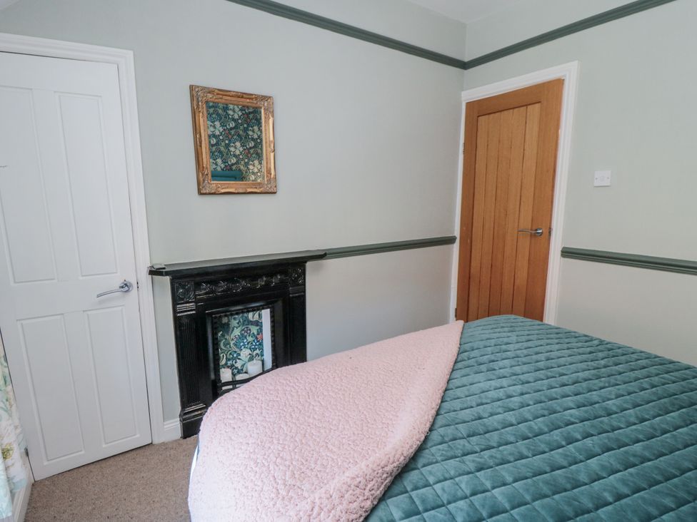 A bedroom with a bed and mirror at Inglenook Cottage in Guisborough