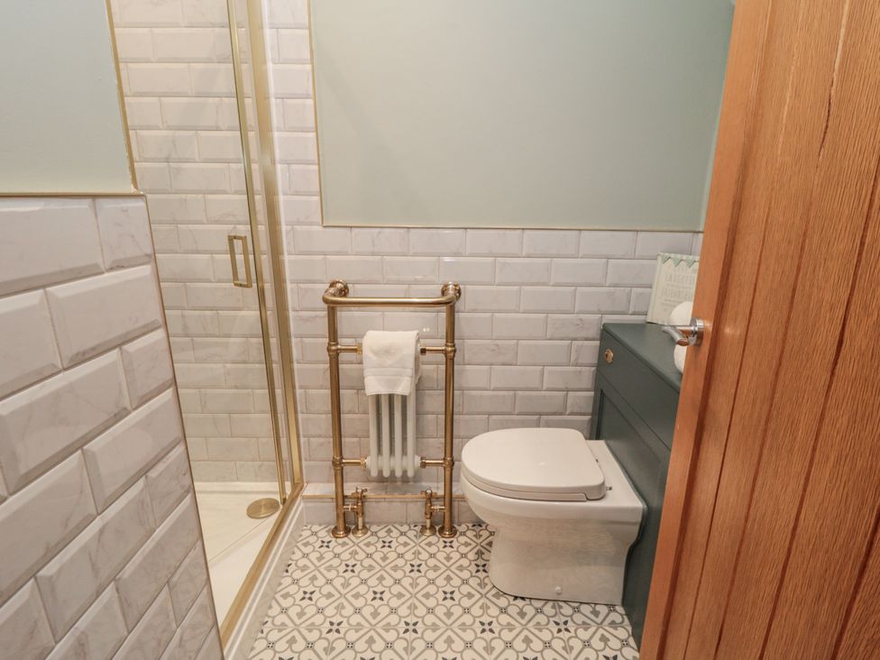 A bathroom with a shower, toilet, and towel rack at Inglenook Cottage Guisborough
