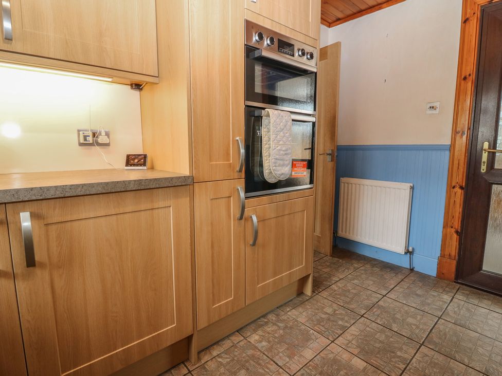 A kitchen with wooden cupboards and an oven at Rowan Cottage Redcastle near Arbroath