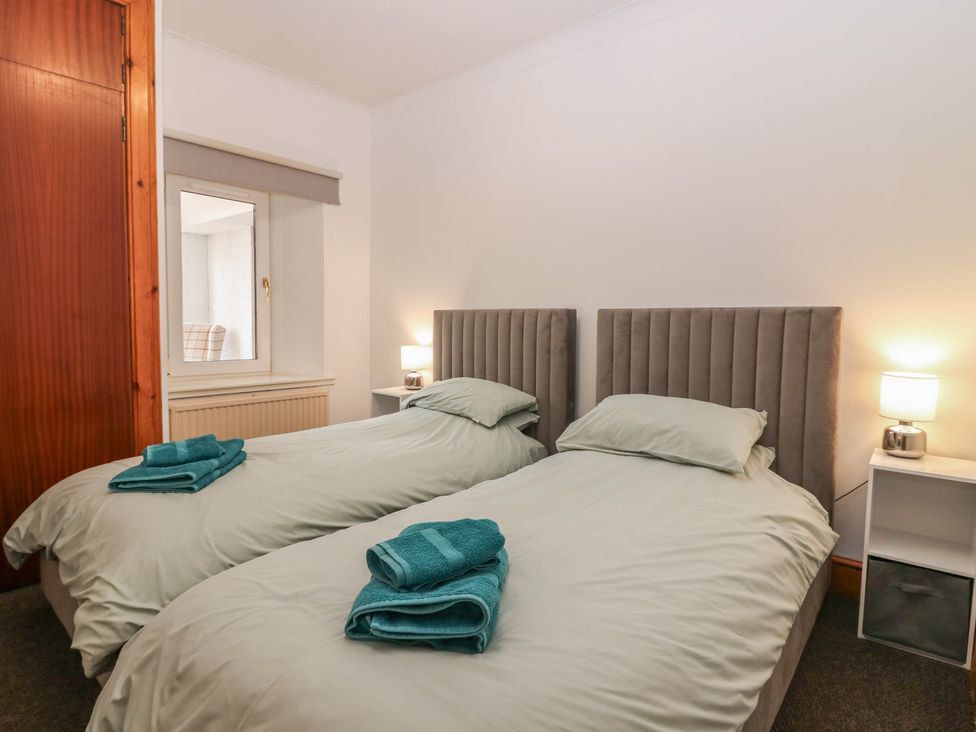 A bedroom with twin beds and bedside table at Rowan Cottage Redcastle near Arbroath
