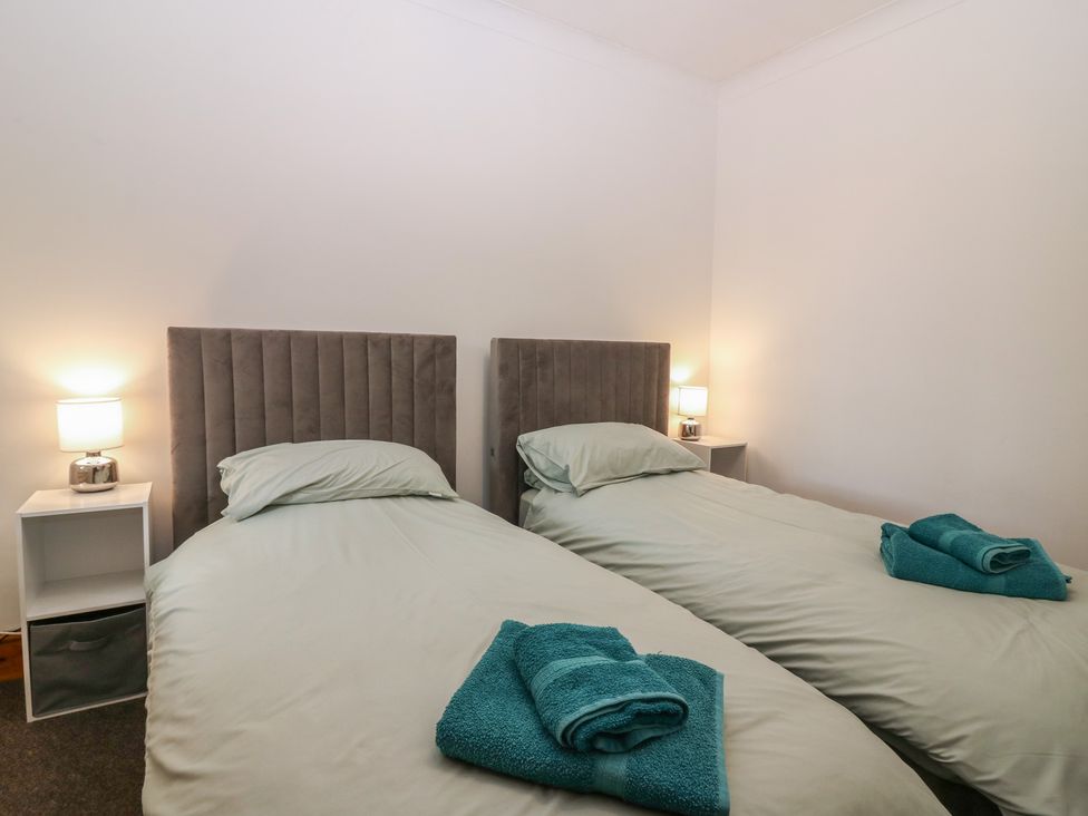 A bedroom with two single beds and bedside table at Rowan Cottage Redcastle near Arbroath