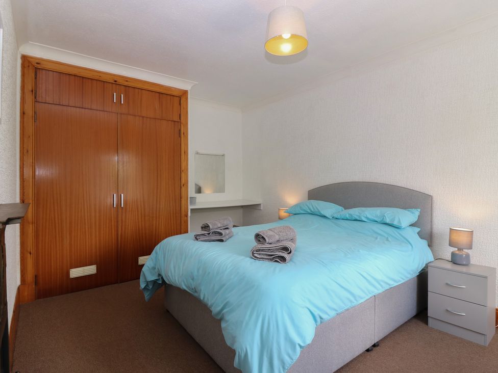 A bedroom with a bed and a wardrobe at Rowan Cottage Redcastle near Arbroath