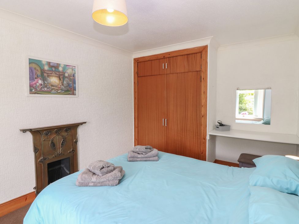 A bedroom with a bed and wardrobe at Rowan Cottage in Redcastle near Arbroath