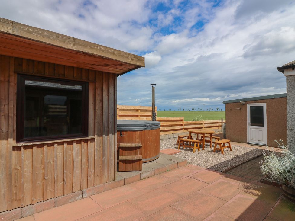 An outdoor area with a hot tub and seating at Rowan Cottage Redcastle near Arbroath