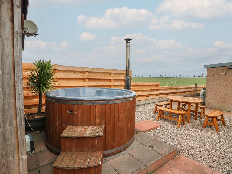 An outdoor area with a hot tub and seating at Rowan Cottage in Redcastle near Arbroath