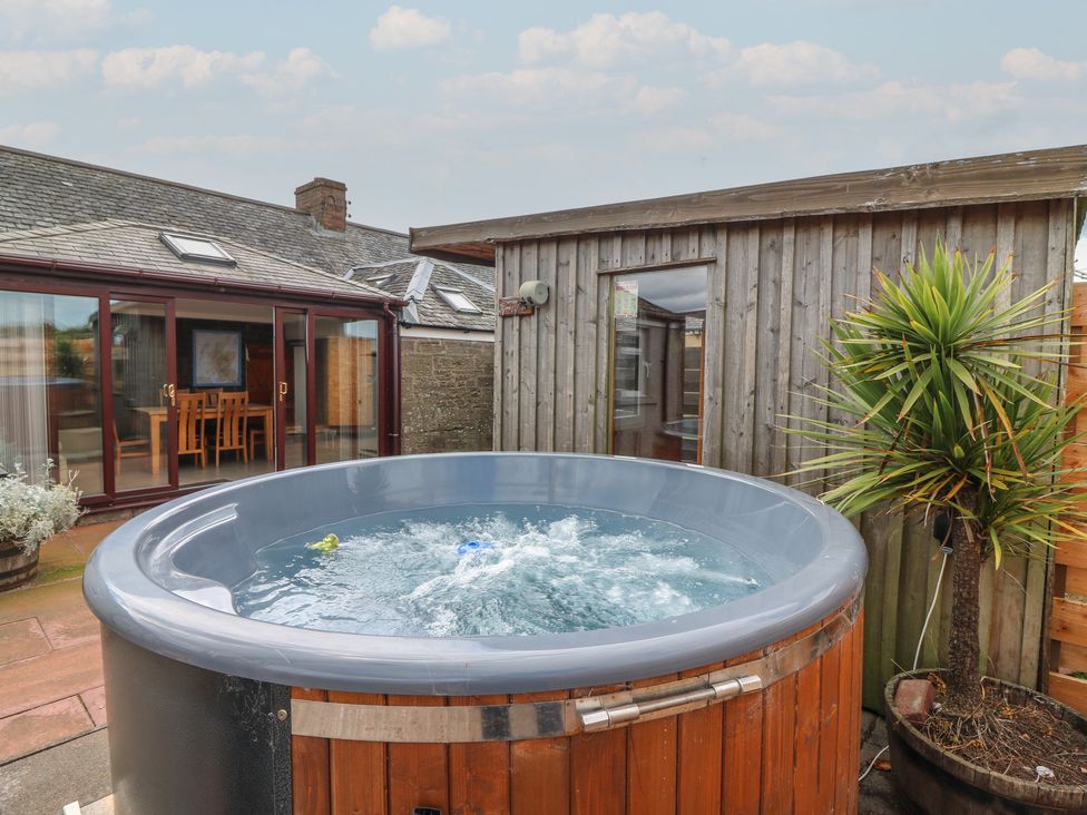 An outdoor area with a hot tub and nearby furniture at Rowan Cottage Redcastle near Arbroath